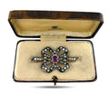 Amethyst and diamond flower brooch in open jewelry case, purple center and pearl-like stones