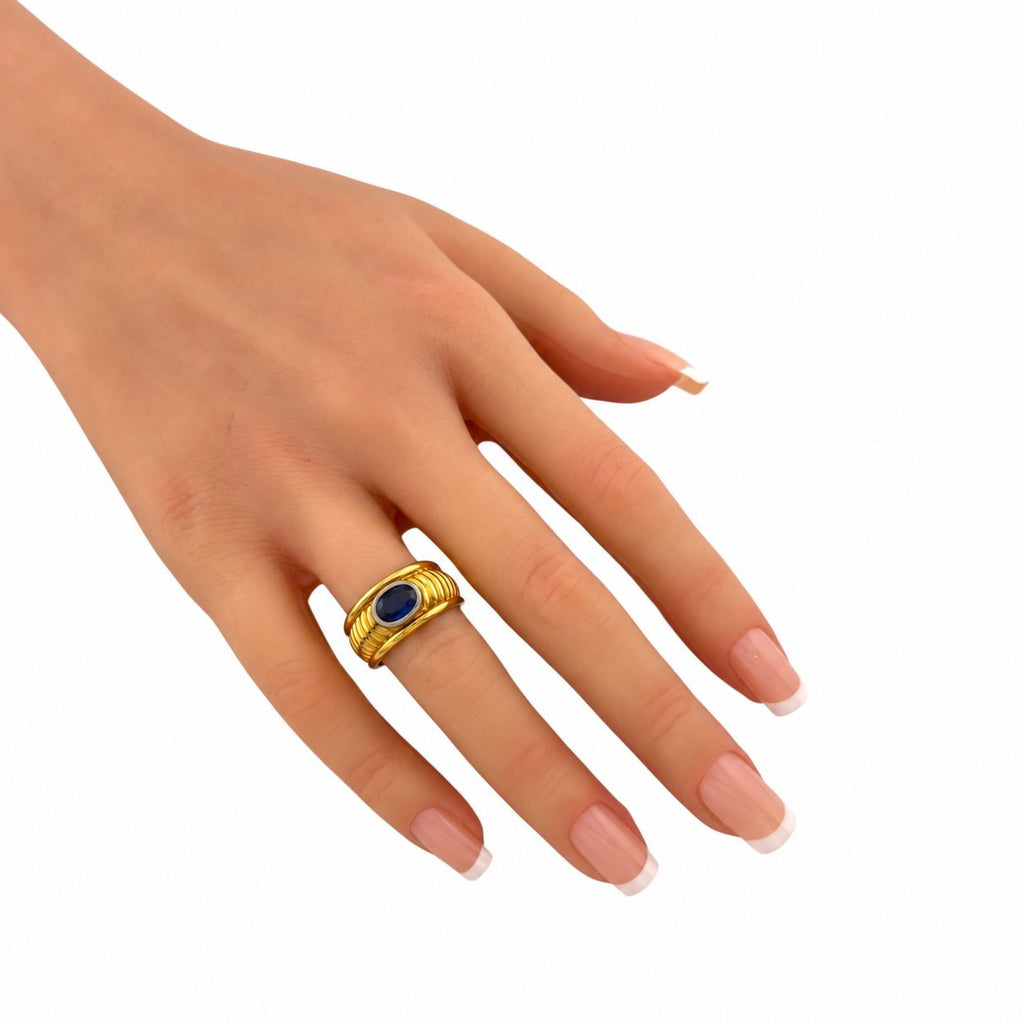 Yellow gold ring with oval blue sapphire on a hand