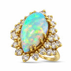 Yellow gold pear opal ring with bright diamond cluster halo and side sparkle