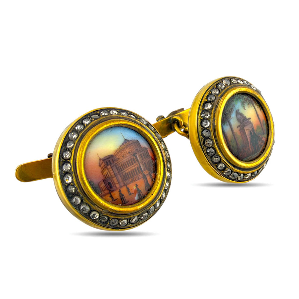 Angled view of scenic enamel cufflinks with yellow gold settings and diamond borders