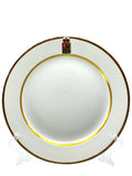 Armorial porcelain plate with gold rim and small crest medallion on white surface