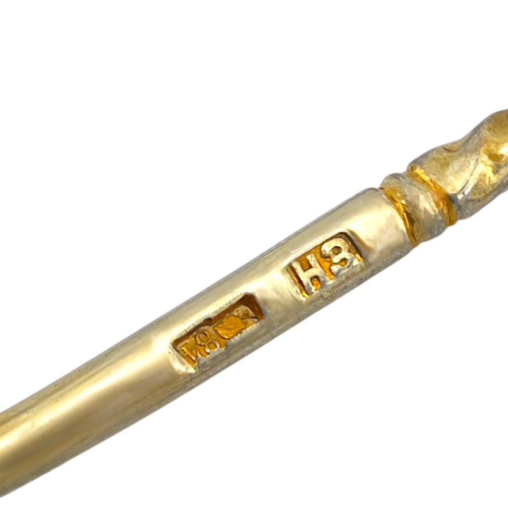 Close-up of antique-style spoon handle with gold hallmark stamps