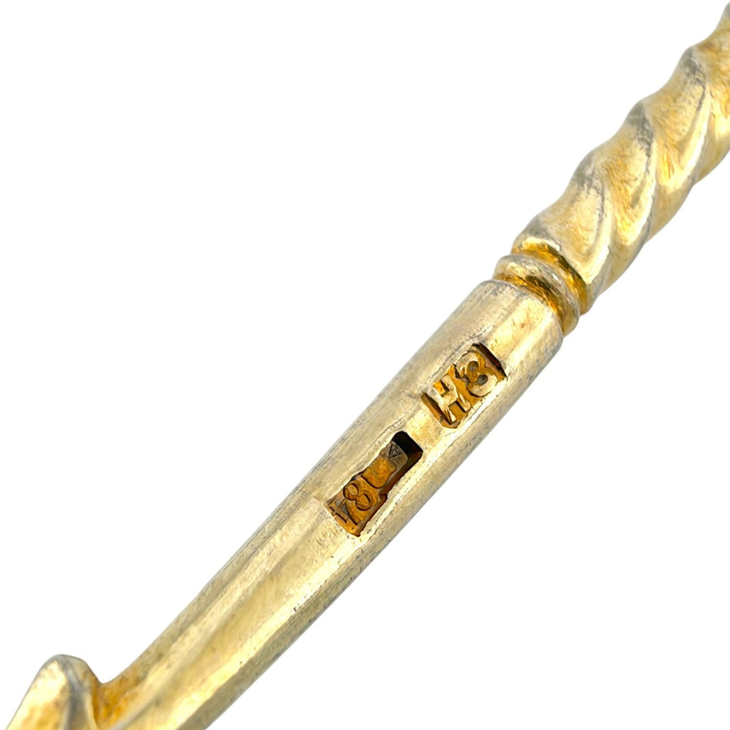 Close-up of gold-tone spoon handle with engraved maker mark and small inlay