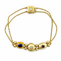 Yellow gold bracelet with square clasp, blue oval gemstone, and diamond accents