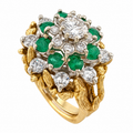 Gold ring with round diamonds and green emerald clusters in a sculpted setting