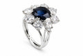 White gold ring with dark blue oval sapphire and diamond halo, prong set