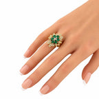 18K yellow gold emerald and diamond cluster ring on finger with green oval center stones