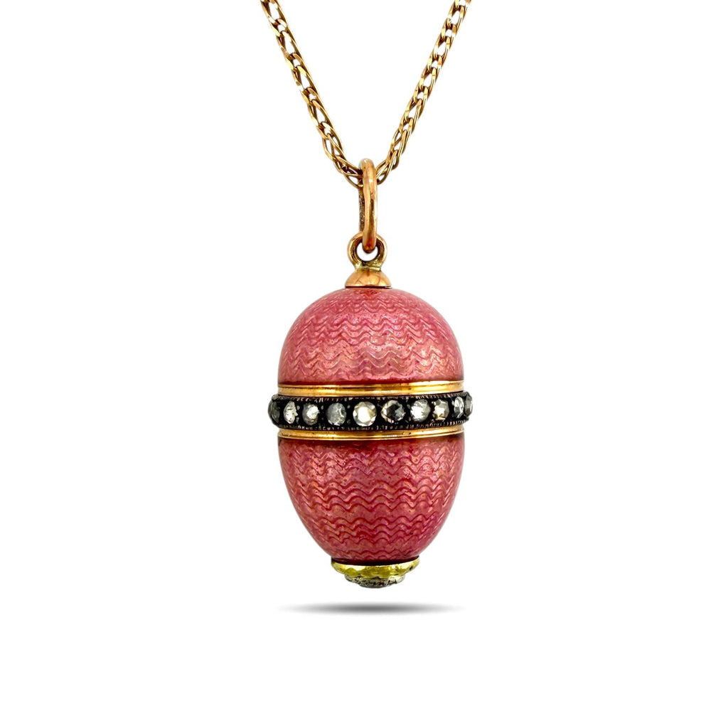 Gold tone egg pendant with pink textured enamel, faceted stone band and necklace chain.
