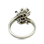 Platinum ring underside view with open basket and prongs holding blue sapphires and diamonds