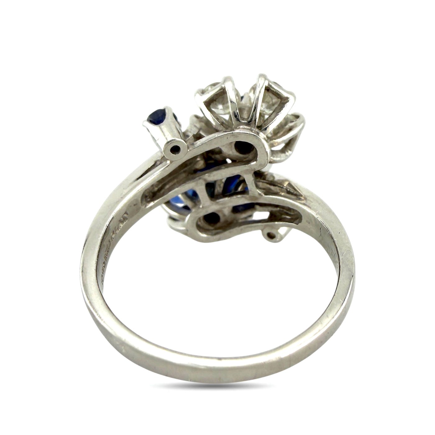Platinum ring underside view with open basket and prongs holding blue sapphires and diamonds