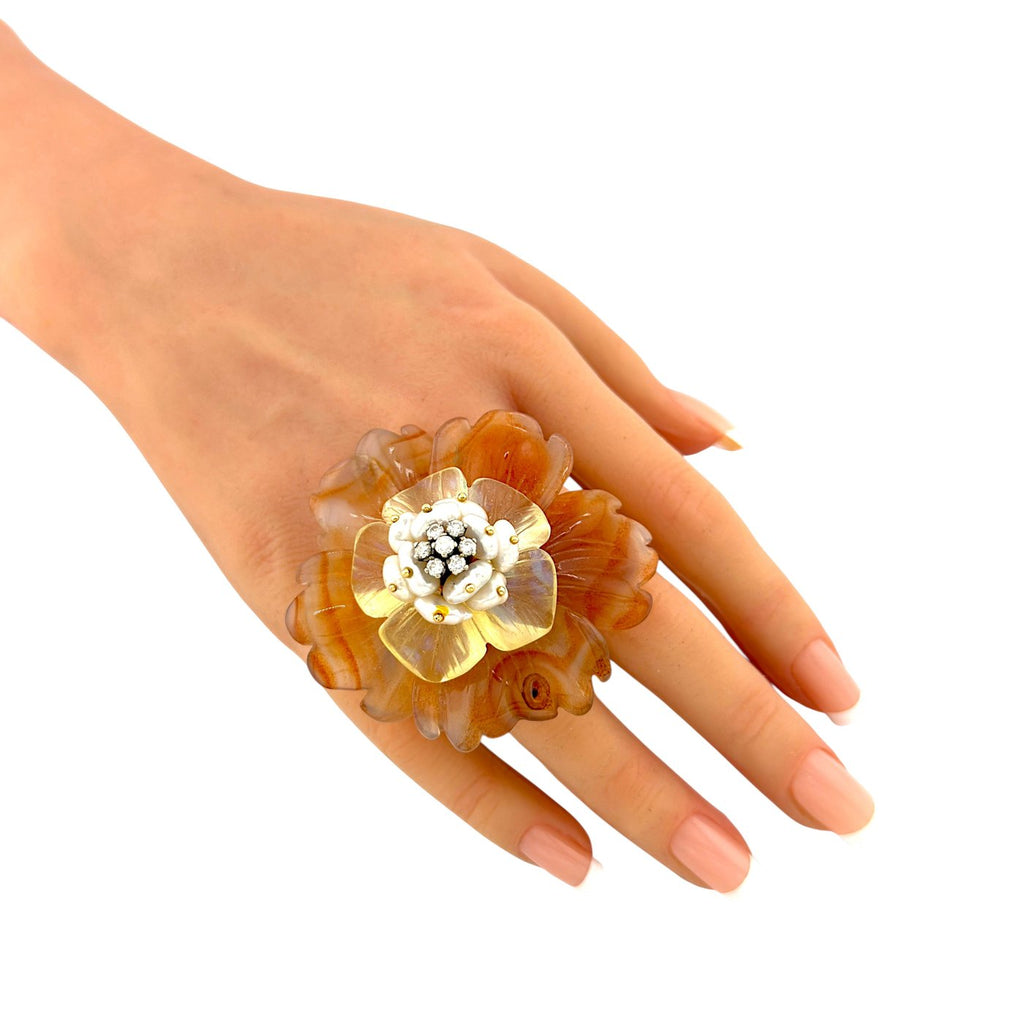 Flower ring on hand: amber petals with pearl-like center and small diamond-like details