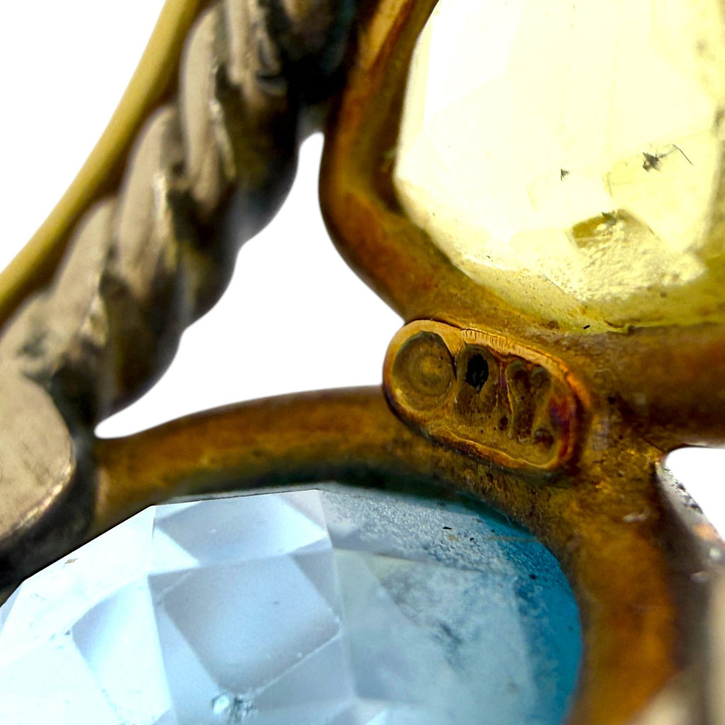 Close-up of prong setting around oval blue gemstone with gold bezel edge