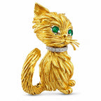 Textured yellow gold cat brooch with emerald eyes and diamond-like collar