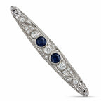 Art deco platinum brooch with two blue sapphires and diamond halo accents, bar pin