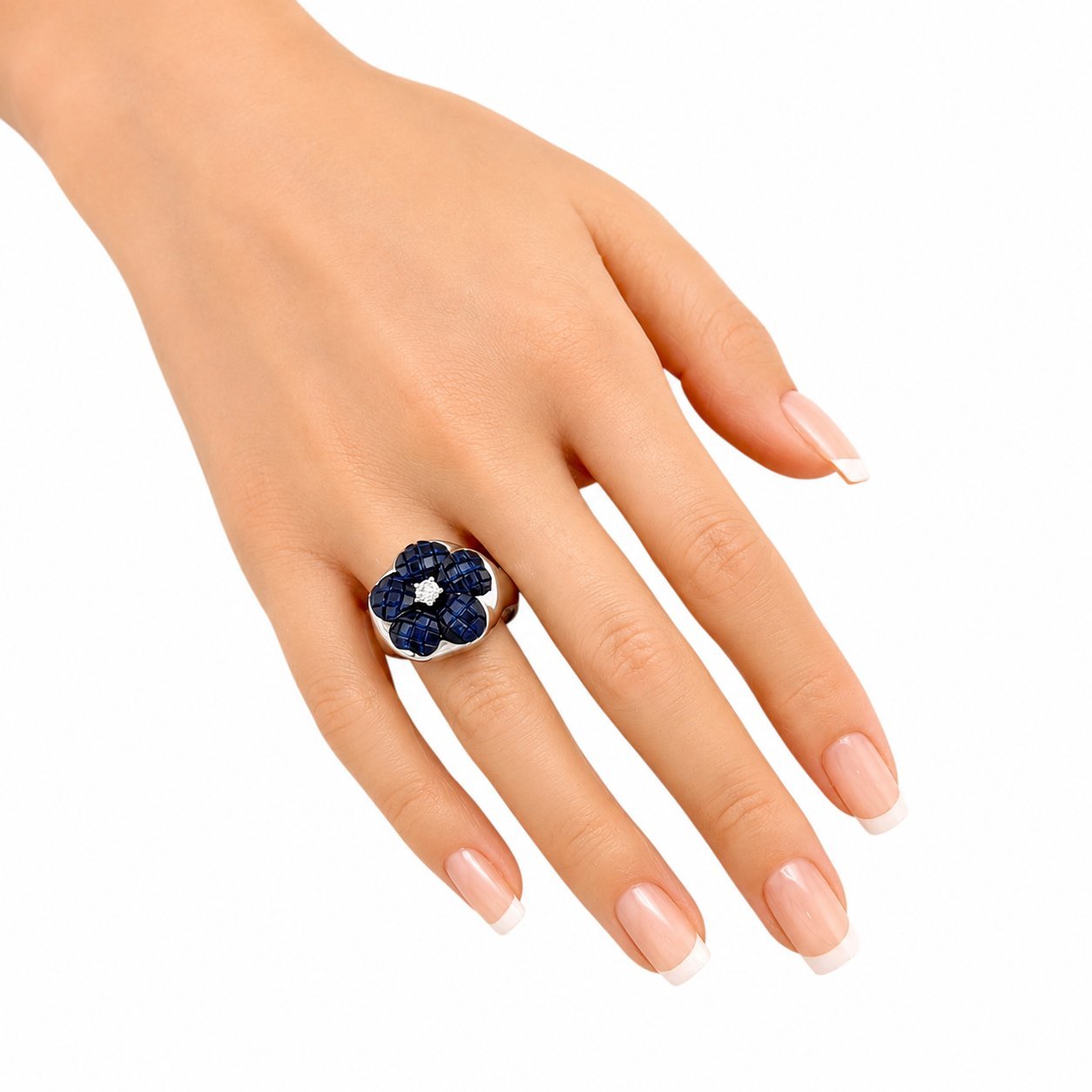 Blue sapphire flower ring on finger with round diamond center, set in white gold
