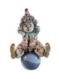 Lladró clown figurine sitting on a blue ball, with ruffled collar