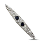 Art deco platinum brooch angled view with two dark blue sapphires and diamond accents