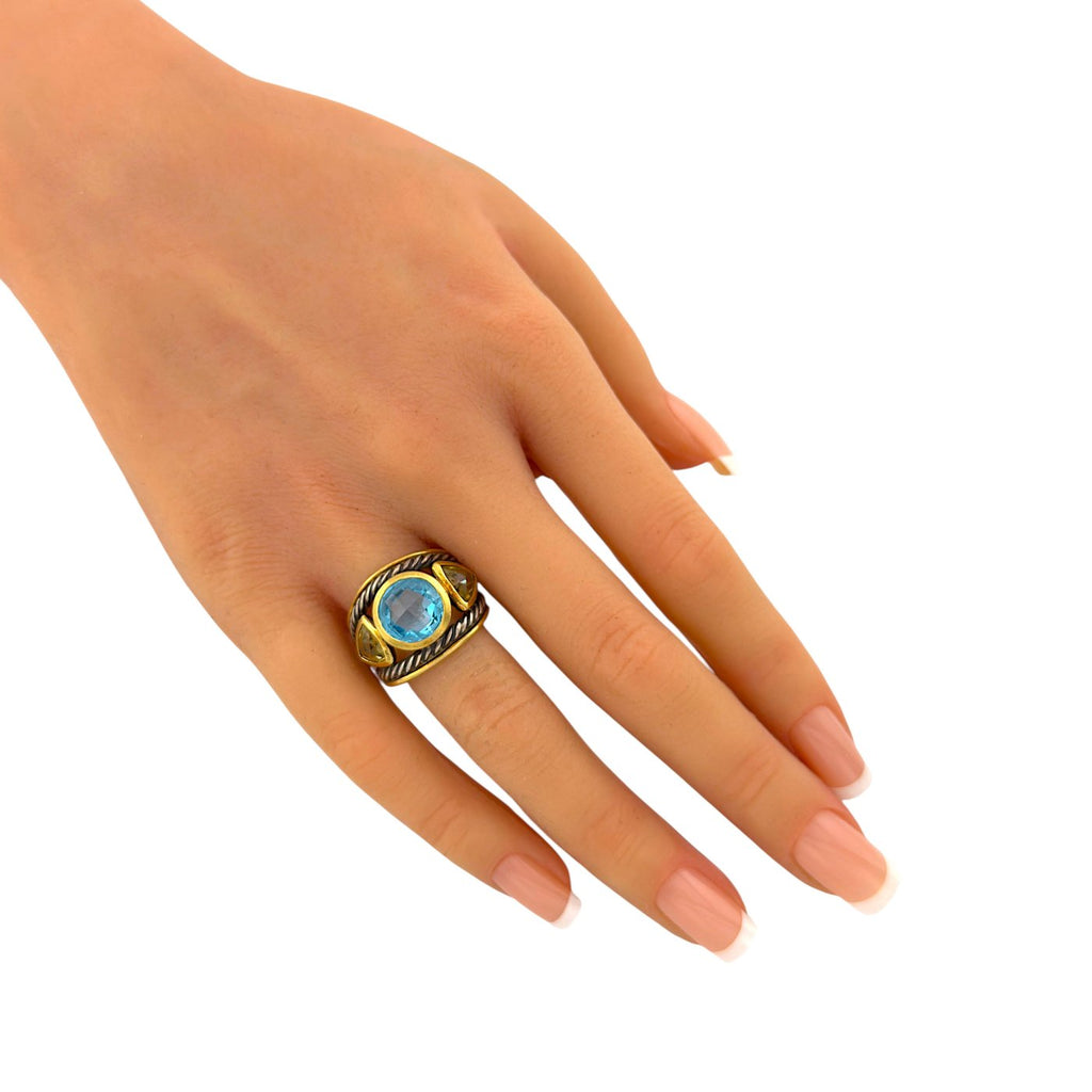 Blue topaz and yellow gemstone ring on finger with gold bezel and braided silver band