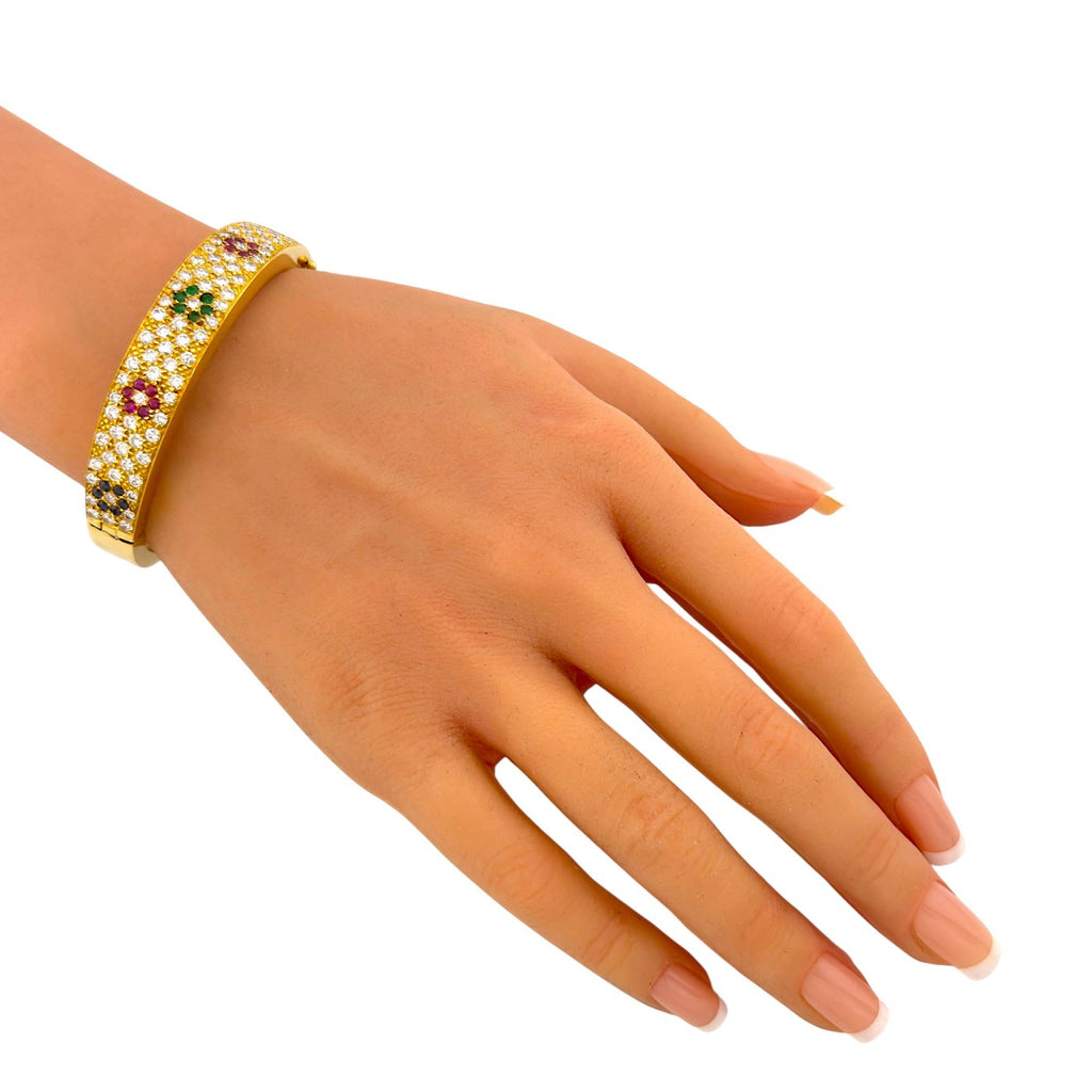 Multicolor diamond pave hinged cuff bracelet on hand with yellow gold setting