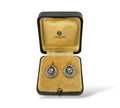 Earrings in display case: gold oval with blue enamel and diamond-like border.