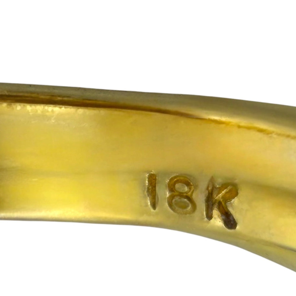 Close-up of 18K hallmark on glossy yellow gold ring band