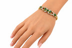 Gold bracelet on a hand featuring emerald oval stones and small round diamond accents