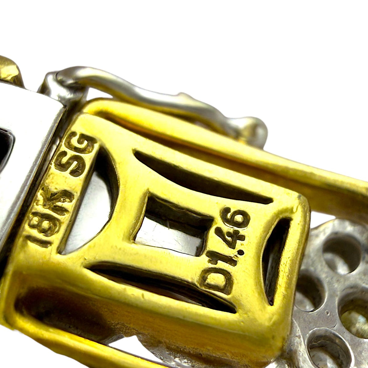 Gold bracelet clasp close-up with engraved markings and surrounding diamond-set links