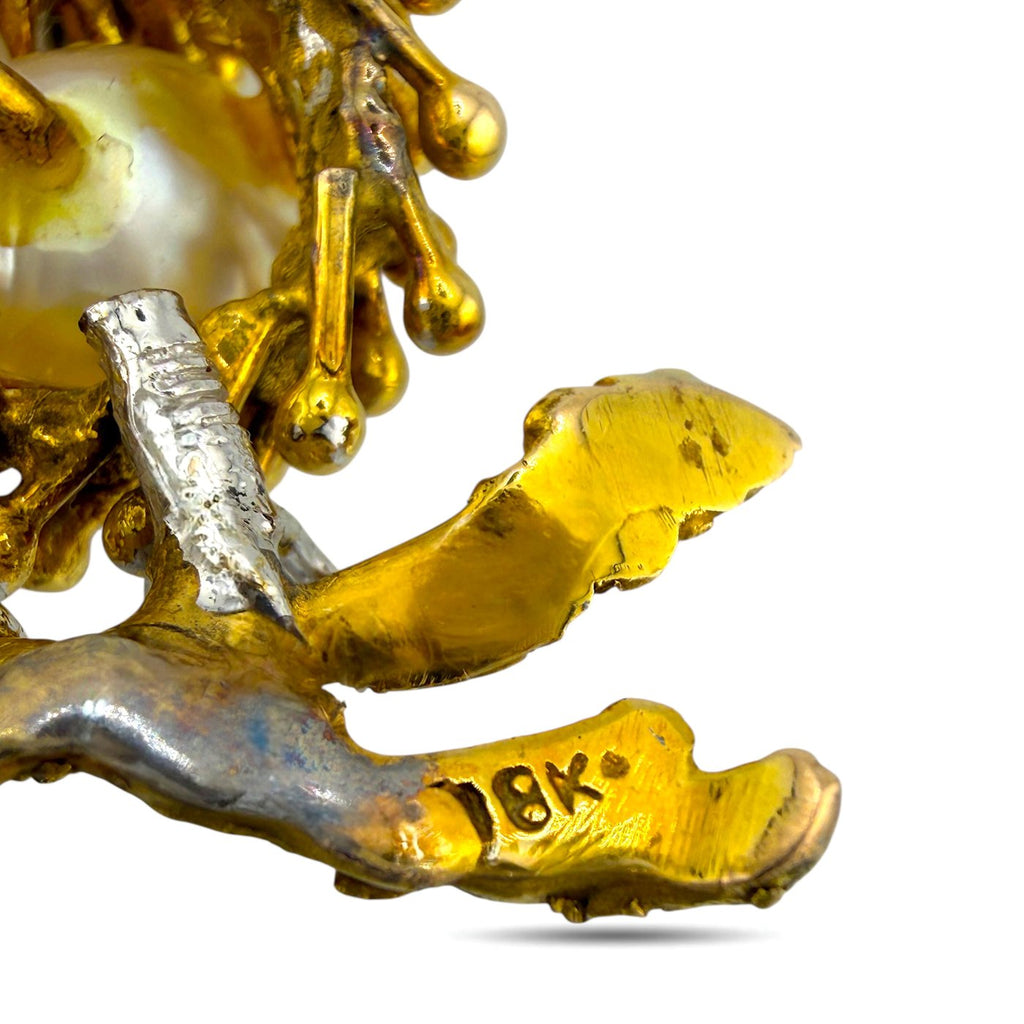 Bird brooch close-up of gold and silver-toned feet with textured detail
