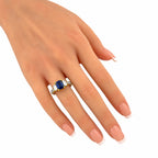 18K yellow gold ring on finger with blue sapphire center and baguette diamond stones