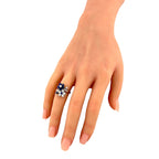 Platinum diamond-and-sapphire flower ring on fingers, blue stones surrounding central diamond cluster