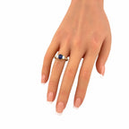 18K yellow gold ring on hand with blue sapphire center and baguette diamond stones