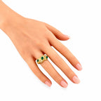 Gold emerald and diamond ring on finger, green center stones with white diamond halo