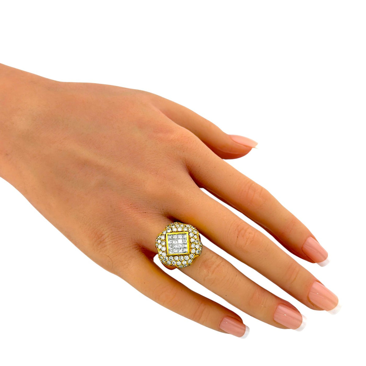Square and round diamond ring worn on a finger, showing its raised gold setting