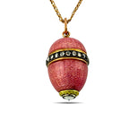 Pink enamel egg pendant with gold tone cap, sparkling stone band, and bottom crystal drop.