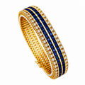 Yellow gold bangle bracelet with blue sapphire grid and diamond bezel stones, angled view.