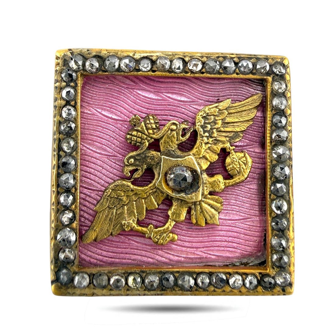Square pink enamel cufflink face with gold bird-and-animal motif and rhinestone border