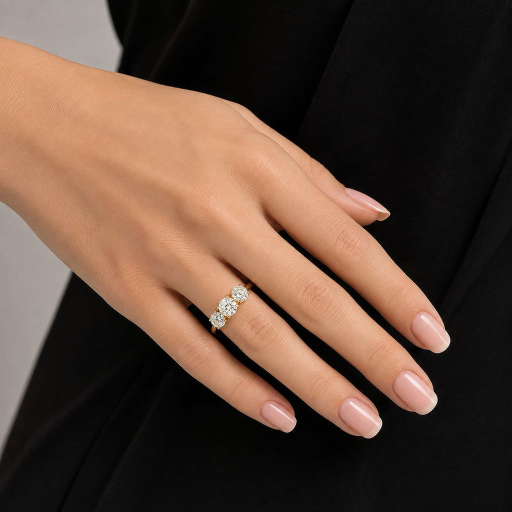 Rose gold three-stone diamond ring on hand, featuring three oval sparkling stones