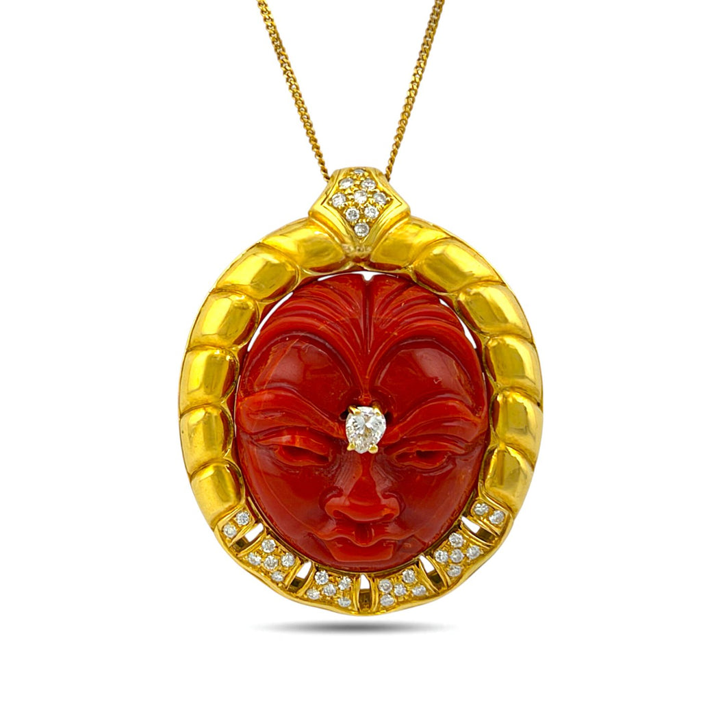 Close-up of carved coral face pendant with diamond details in a gold setting