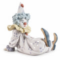 Porcelain clown figurine with blue hat, seated with legs out and gold scarf