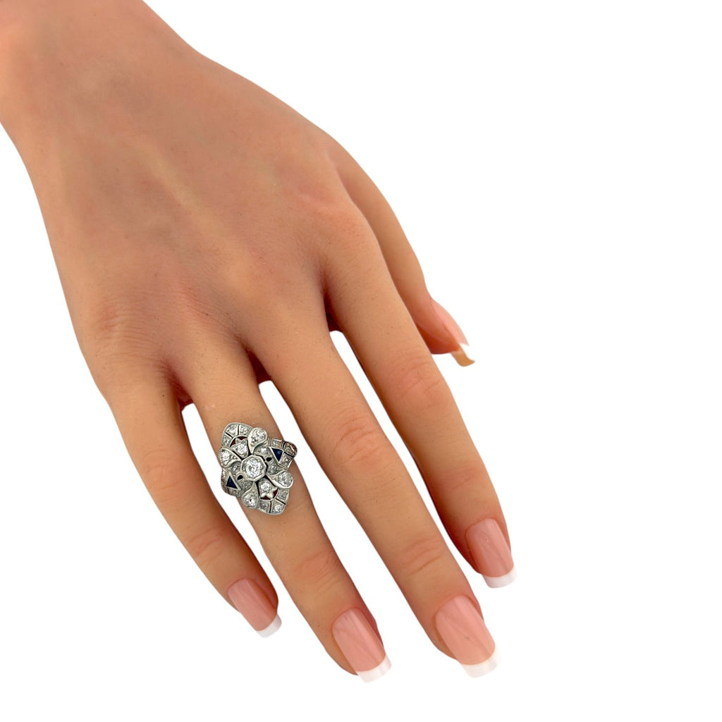 Diamond and sapphire art deco ring worn on finger, with round stones and blue side detail