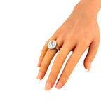 White gold ring on finger with round center diamond in circular setting