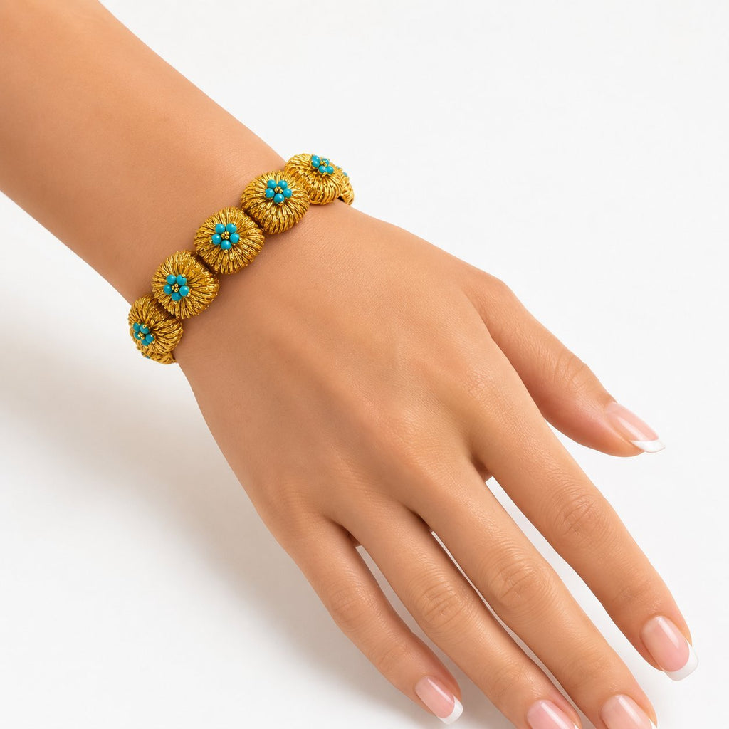 Turquoise bead bracelet on wrist, 18K yellow gold with blue flower motifs on textured links