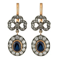Gold and diamond drop earrings with dark blue oval center stone and filigree halos