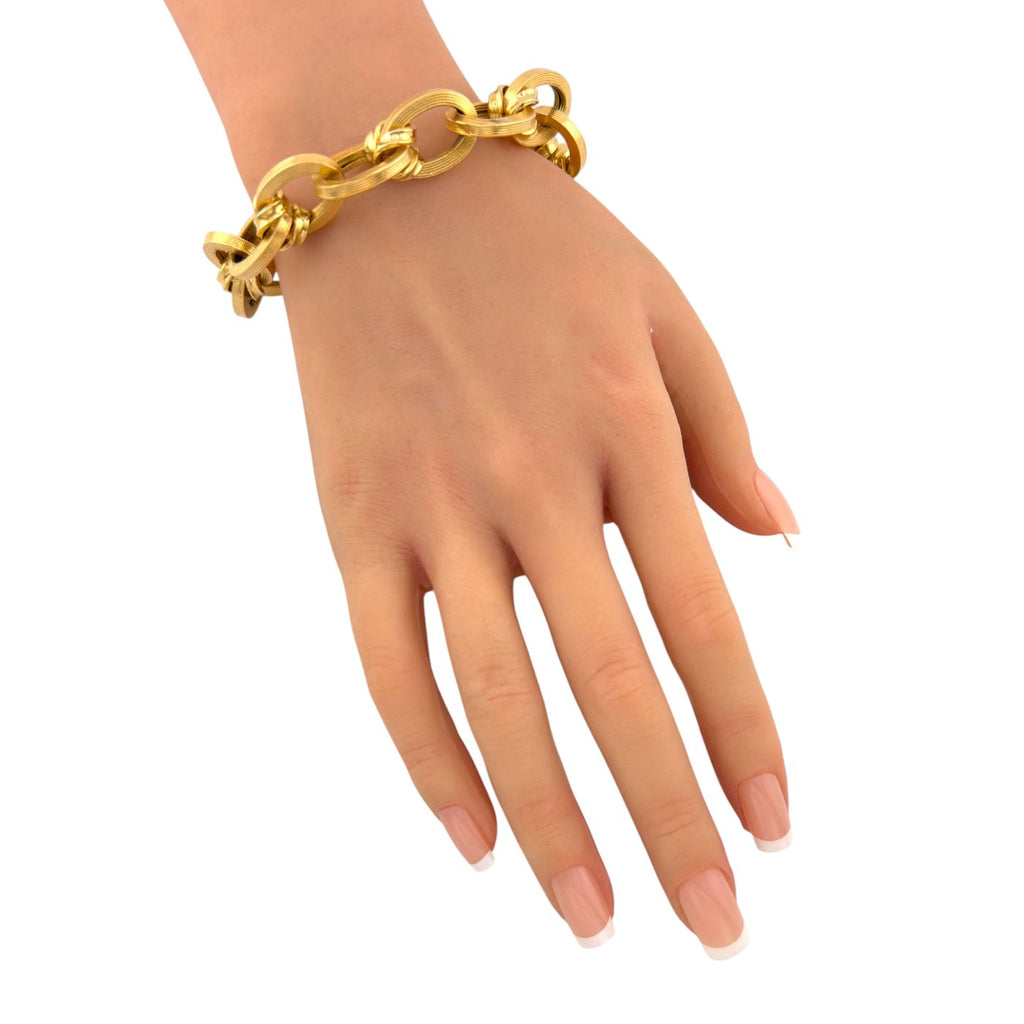 18K yellow gold textured oval link bracelet on hand, bright interlocking oval links