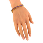 Rainbow gemstone bracelet worn on the wrist, with purple and pink stones