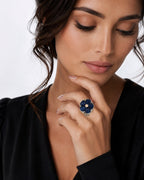 Woman wearing a blue sapphire flower ring with a round diamond center on a white gold band