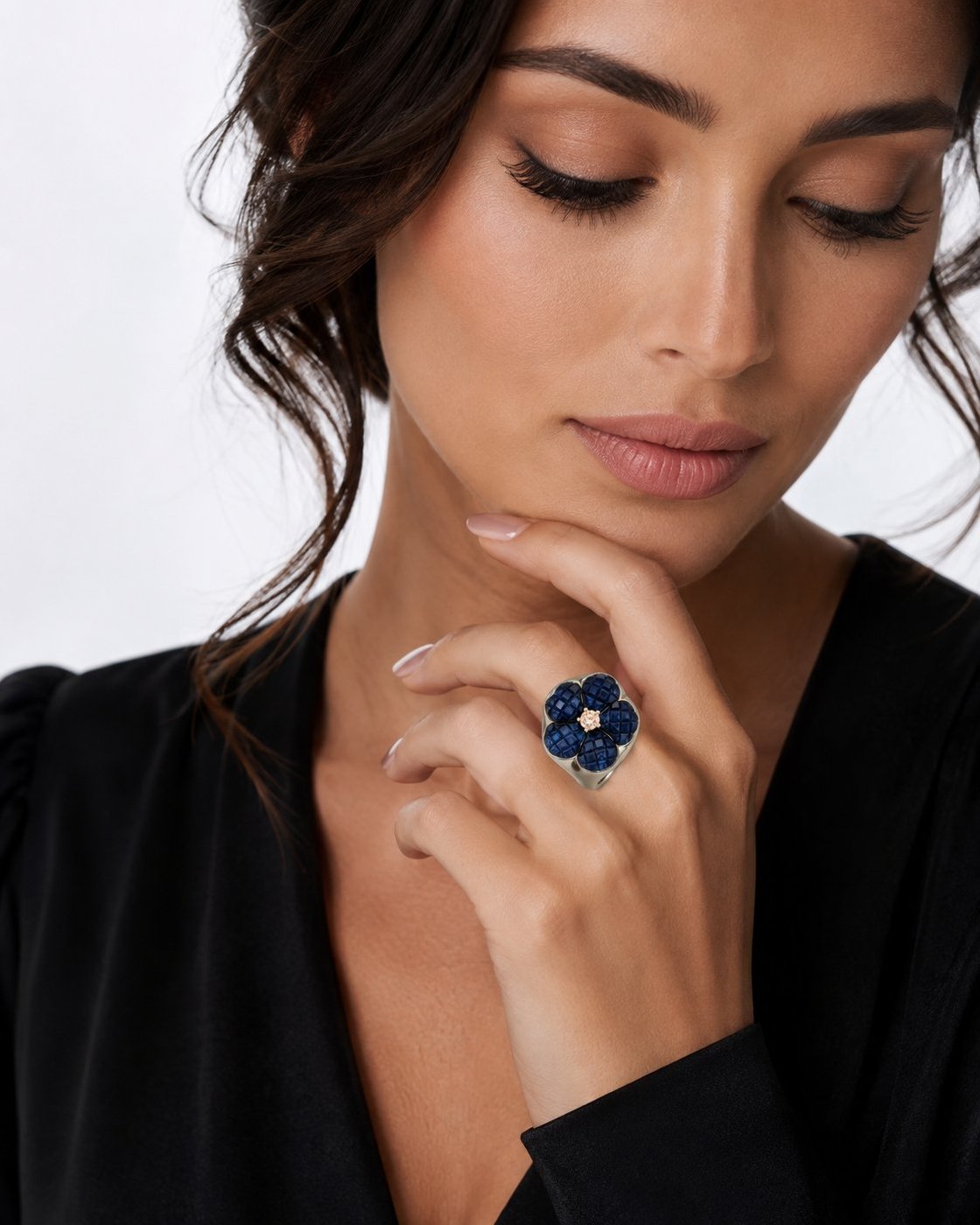 Woman wearing a blue sapphire flower ring with a round diamond center on a white gold band