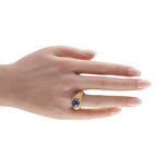 18k yellow gold ring with oval blue sapphire on finger, ornate carved band