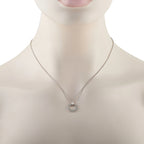 White gold circle diamond pendant on a fine chain worn at the neckline