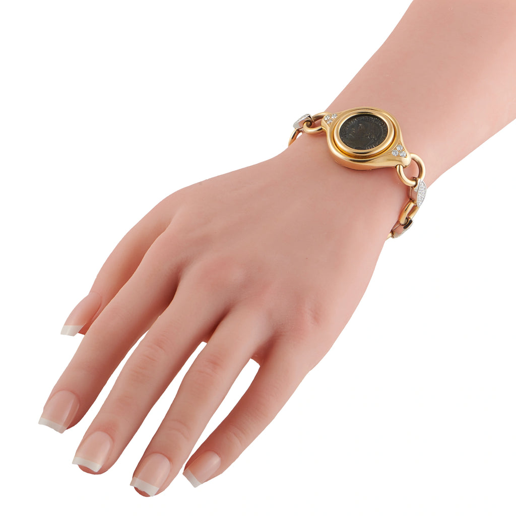 Yellow gold bracelet on wrist with black coin medallion and diamond-accent links